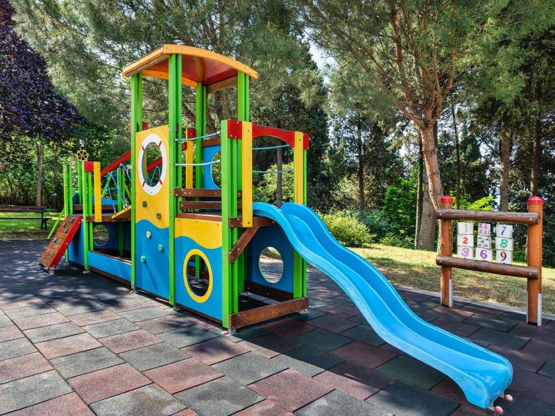 Area giochi colorata con scivolo in un'area verde esterna di un hotel.