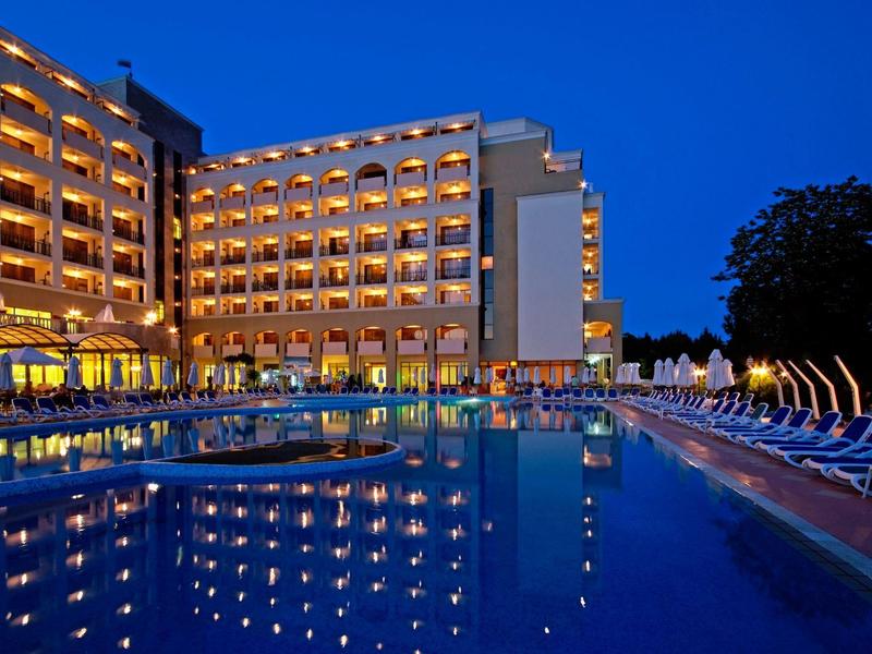 Hotel illuminato con grande piscina esterna e lettini di notte