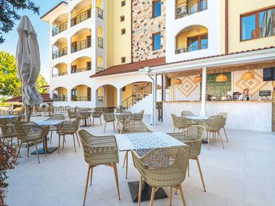 Leerer Außenbereich eines Hotels mit Tischen und Stühlen auf heller Terrasse bei Tageslicht.