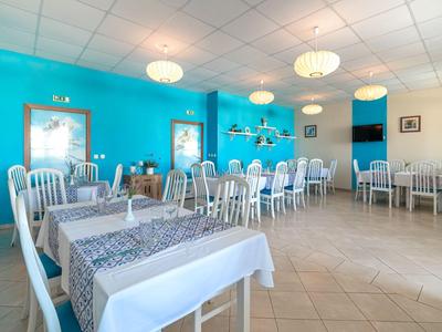 Helles Restaurant mit weißen Tischen, türkisfarbenen Wänden und moderner Einrichtung.