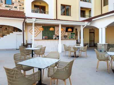 Innenhof eines Hotels mit Tischen, Stühlen und einer Bar mit Holzregalen.