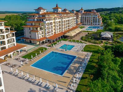 Großes Resort mit mehreren Außenpools, Liegen und grüner Umgebung in ländlicher Gegend.