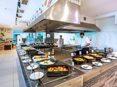 Buffet mit verschiedenen Speisen und Köchen in einer modernen Hotelküche.