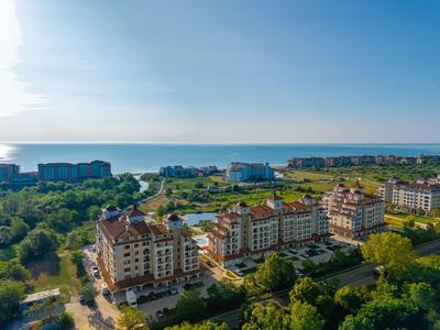 Luftaufnahme eines Hotels in Küstennähe mit umliegendem Grün und klarem Himmel.