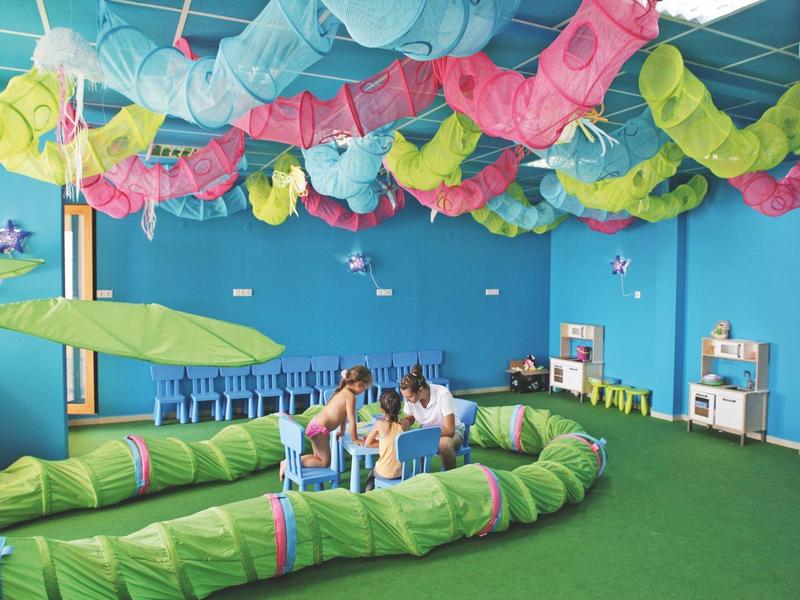 Colorful playroom with child-friendly climbing and play structures and a ceiling adorned with colorful fabric strips.