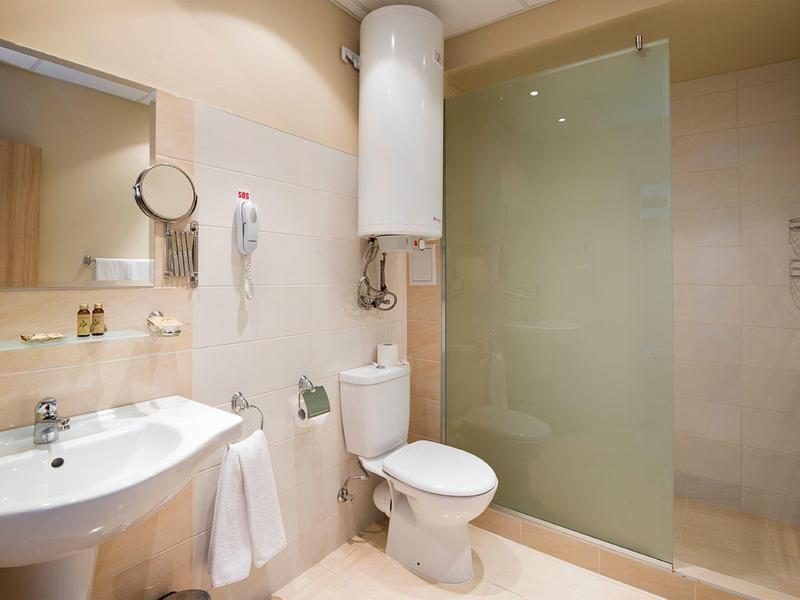 Bright bathroom with white sink, toilet, and walk-in shower with glass partition.