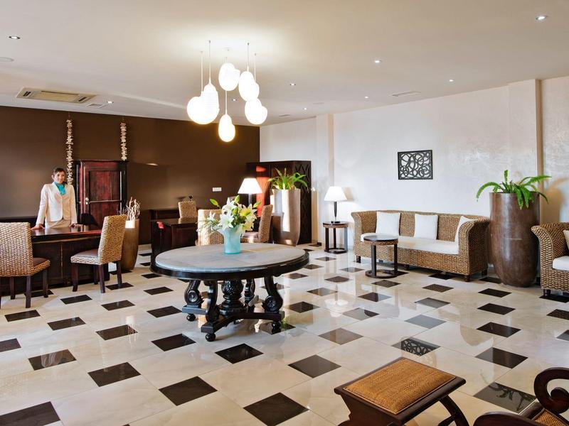 Bright hotel lobby with round table, comfortable seating, and decorative plants.