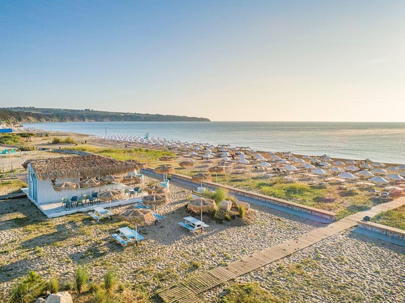 Beach with many umbrellas and loungers on a sunny day with clear sky.