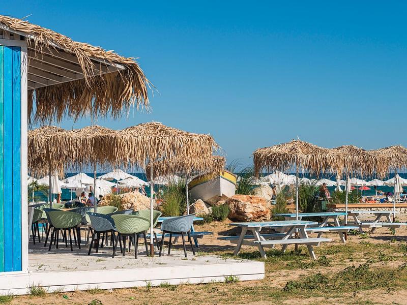Beach bar with straw roofs and seating under a blue sky