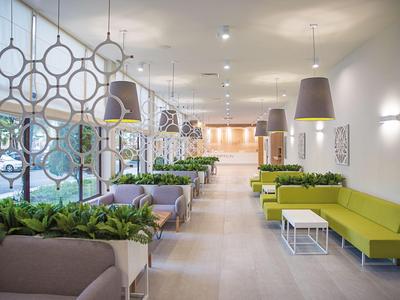 Moderne Hotellobby mit grünen Sofas, Pflanzen und hellen Lampen in elegantem Ambiente