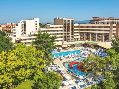 Velký vícepatrový hotel s bazénem a slunečníky obklopený stromy