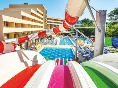Bunte Wasserrutsche mit Blick auf einen Hotelpool und Liegestühle an einem sonnigen Tag