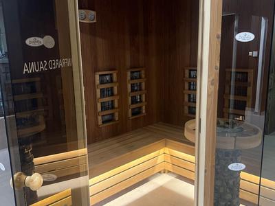 Dřevěná sauna se skleněnými dveřmi a nepřímým osvětlením pod lavičkou.