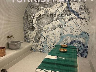 Moderní turecká lázeňská místnost s mozaikovou zdí a masážním stolem