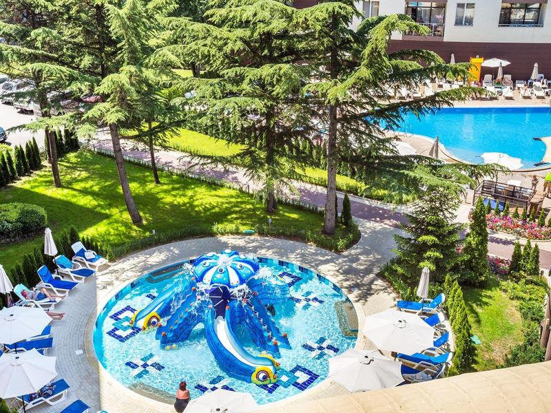 Venkovní bazén s dětským bazénem ve tvaru velryby a lehátky.