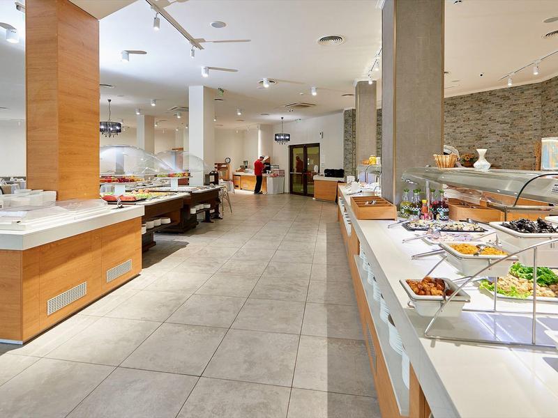 Světlá hotelová bufetová místnost s různými pokrmy a moderním zařízením.