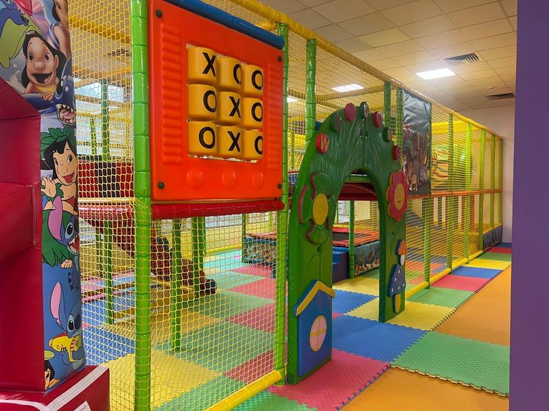 Barevné vnitřní dětské hřiště s horolezeckou konstrukcí, měkkými rohožemi a hrou piškvorky.