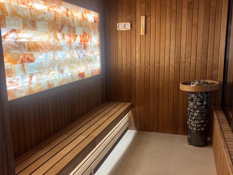Saunová místnost s dřevěnými stěnami, lavicí a osvětleným dekorativním kamenným oknem