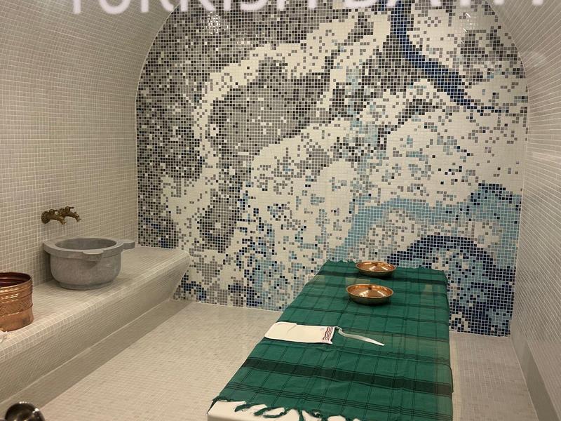 Moderní turecká lázeňská místnost s mozaikovou zdí a masážním stolem