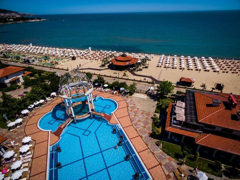Großer blauer Außenpool mit Brücke, Sonnenschirmen und direktem Zugang zum Strand und Meer.