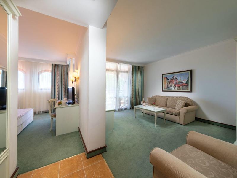 Helles Wohnzimmer mit grünen Teppich, hellbraunen Sofas und großem Wandbild.