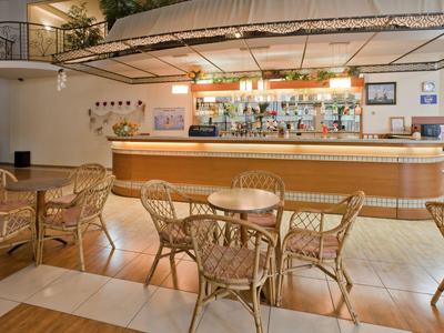 Cozy hotel bar with wicker chairs and a lit-up counter.