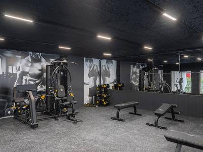 Moderner Fitnessraum mit Kraftgeräten, Hanteln und großen Spiegelwänden in einem Hotel.