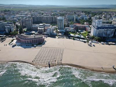 Beach with sand patterns in front of a city with hotels and buildings by the sea