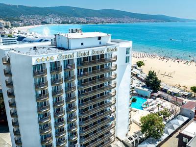 High-rise hotel with balconies next to a sandy beach and blue sea