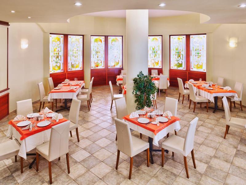 Brightly lit breakfast room with modern tables and chairs in warm colors.