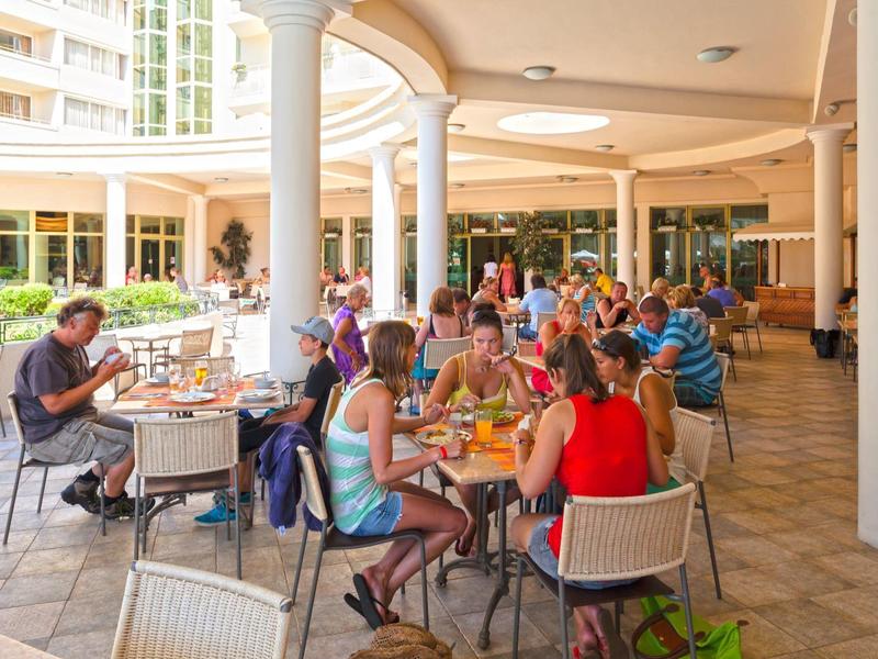People sit and eat in a covered outdoor area of a hotel restaurant.