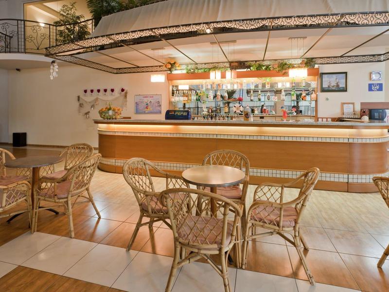 Cozy hotel bar with wicker chairs and a lit-up counter.