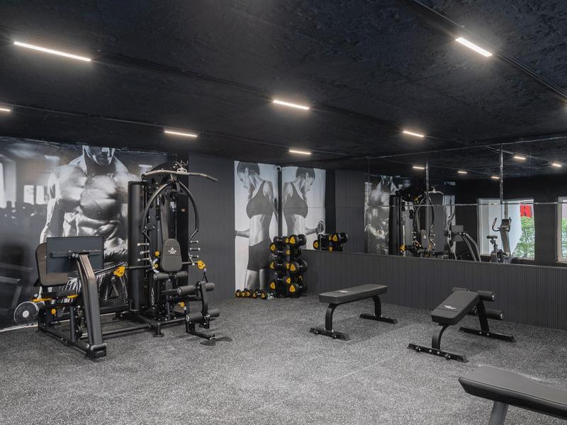 Modern gym with equipment, dumbbells, and large wall mirrors