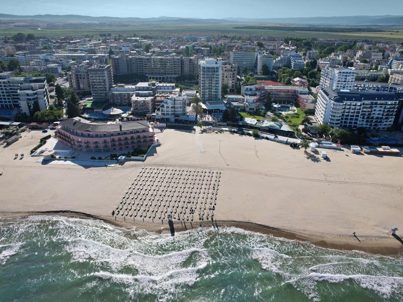 Beach with sand patterns in front of a city with hotels and buildings by the sea