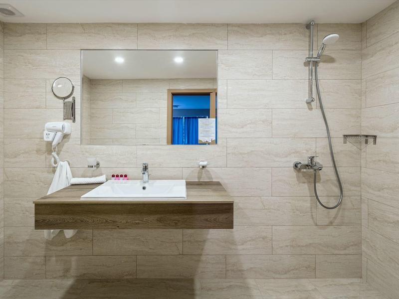 Modern bathroom with wall mirror, sink, hairdryer, and walk-in shower.