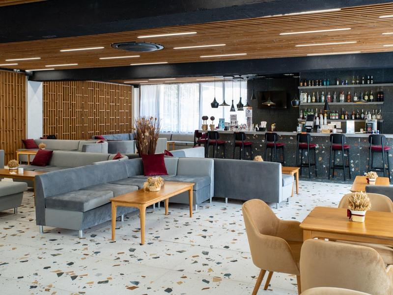 Modern hotel lounge area with gray sofas and a bar in the background.