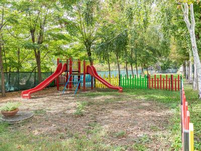Kinderspielplatz mit Rutsche und Klettergerüst in einem von Bäumen umgebenen Garten.