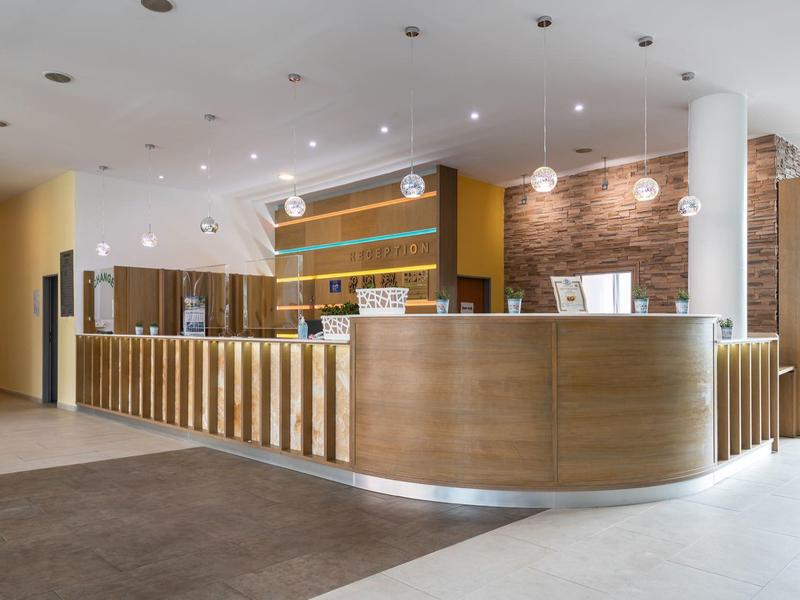 Moderne hotelreceptie met verlicht houten balie en bakstenen muur op de achtergrond.