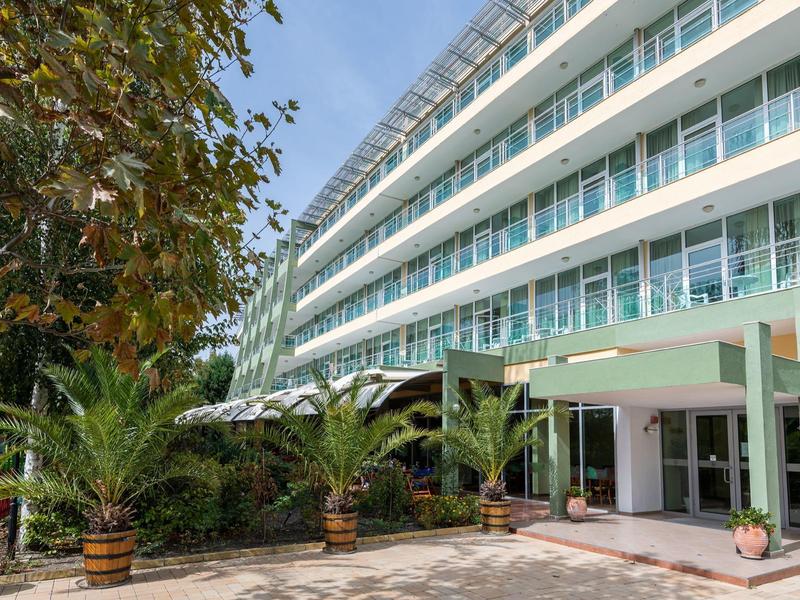 Modern hotelgebouw met ruime ingang en decoratieve palmbomen in potten.