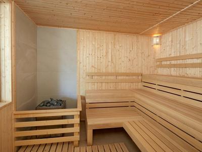 Sauna mit mehrstöckigen Holzbänken, Holzwänden und einem Fenster, hell und sauber gestaltet.