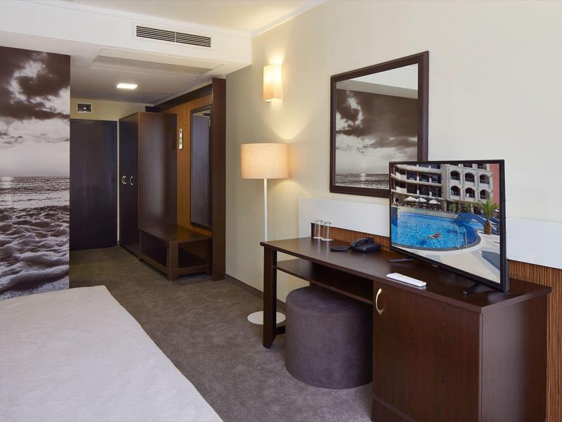 Modern eingerichtetes Hotelzimmer mit Hell-Dunkel-Kontrasten, TV, Lampe und großem Foto an der Wand.