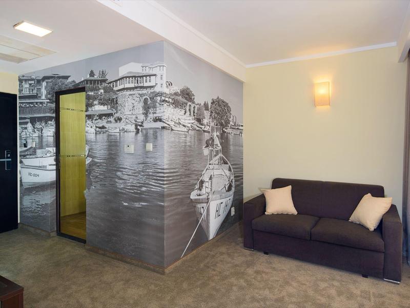 Modernes Zimmer mit grauem Sofa, Kissen und Wandbild in Schwarzweiß eines Flussufers mit Brücke.