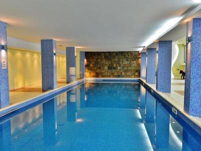 Piscina interior con columnas azules y luz cálida, ideal para vacaciones en hotel y relajación.