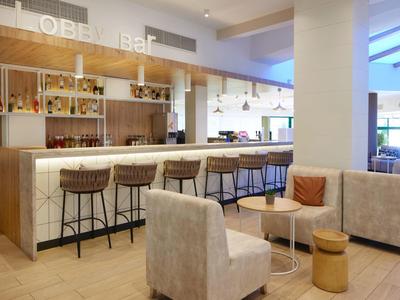 Moderna zona de bar de hotel con taburetes, asientos y ambiente acogedor.