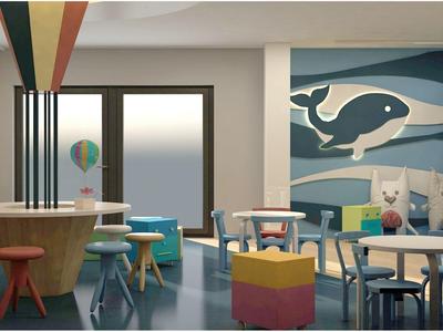 Zona infantil luminosa y colorida con mesas, sillas de colores y un mural de ballena en la pared.