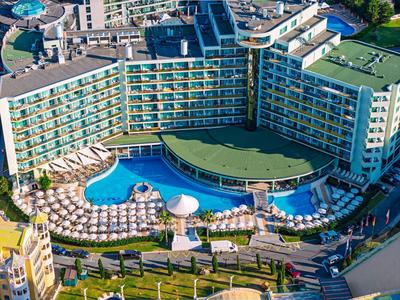 Vista aérea de un hotel moderno con una gran piscina al aire libre y tumbonas.