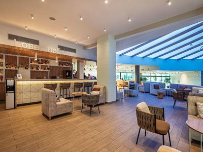 Moderner Hotellounge-Bereich mit Bar, Sesseln und großen Fenstern