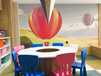 Habitación colorida con mesa redonda, sillas y un gran mural de globo aerostático.