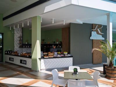 Modernes Hotelrestaurant mit Buffetbereich und Außensitzplätzen, helle Einrichtung und Pflanzen.