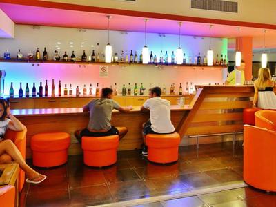 Moderne Hotelbar mit buntem LED-Licht, orangefarbenen Sitzgelegenheiten und Gästen an der Theke.